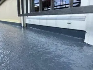 Glatte graue Abdichtung an einer Hauswand neben einem Fenster