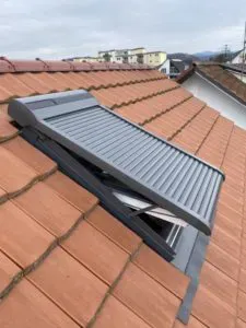 Geschlossener Metallrollladen auf einem Dachfenster im Ziegeldach