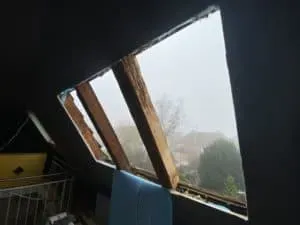 Beschädigtes Dachgeschoss mit fehlenden Platten und freiliegenden Holzbalken