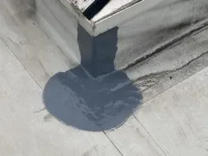 Graue Abdichtung um eine Metallecke auf einer flachen hellen Fläche