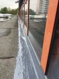 Fensterreihe mit frischer grauer Abdichtung am Sockel