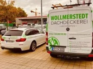 Ein Transporter und ein Auto sind geparkt; auf dem Transporter steht die Aufschrift „Wollmerstedt Dachdeckerei“, ein örtliches Dachdeckerunternehmen.