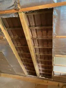 Teilweise geöffnete Decke mit Holzbalken, Dachziegeln und Dämmung