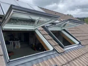 Zwei geöffnete Dachfenster in einem Ziegeldach mit Blick in den Dachraum