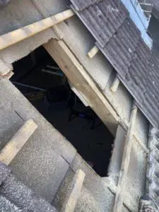 Großes Loch in einem Ziegeldach mit freiliegenden Holzbalken