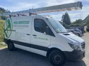 Weißer Transporter mit Dachleiter und Aufschrift „Wollmerstedt Dachdeckerei“