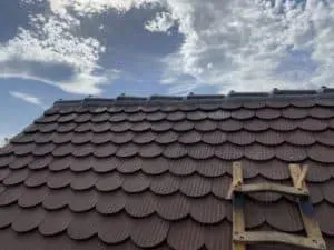 Rotes Ziegeldach mit kleiner Holzleiter unter leicht bewölktem Himmel