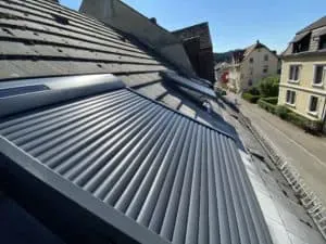 Metallrollläden vor den Dachfenstern eines Wohnhauses an einem sonnigen Tag