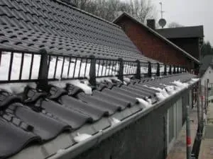 Schwarzes Ziegeldach mit Schneefang und Schneefang am Rand, fachmännisch montiert von einer professionellen Dachdeckerei.