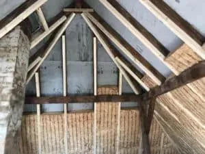 Holzbalken und Sprühschaumdämmung in einem unfertigen Dachboden