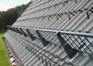 Metalldach mit Schneefanggittern, im Hintergrund Bäume