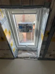 Teilweise geöffnetes Dachfenster mit Dämmung ringsum, Blick auf das Ziegeldach