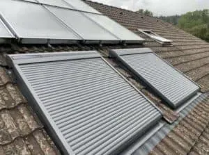 Zwei geschlossene Rollläden und Solarmodule auf einem Ziegeldach