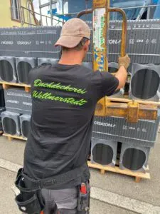 Mitarbeiter transportiert eine Palette Dachziegel mit dem Gabelstapler
